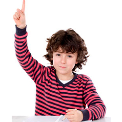 Boy with raised arm and index finger pointing, wearing a striped shirt and a pencil on the table.