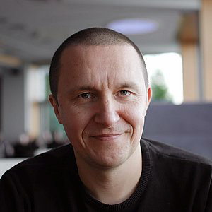 Retrato de un hombre con cabello corto y oscuro, de aspecto maduro, con una sonrisa suave.